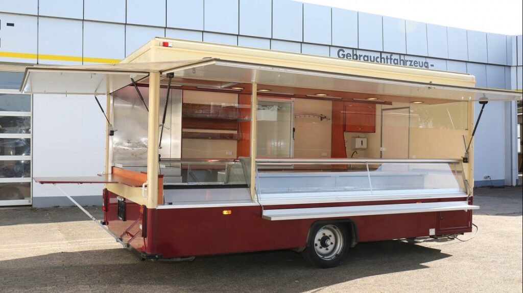 Verkaufsseite im Heck mit ausklappbaren Esstisch, Sichtkühlschrank und weitere Kühlschränke vorhanden.-Thekenarbeitsfläche mit Edelstahl erneuert. Vorhandenes Bratgerät (Propangas) ohne Gewährleistung wird lose beigestellt.