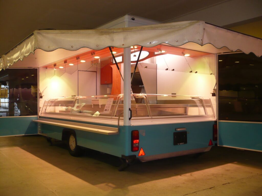 Sehr schöner Fisch-Verkaufsanhänger mit Panoramatheke über Eck. UBERT Doppelfriteuse sowie Abzugshaube.-Arbeitsflächen komplett aus Edelstahl, Lampenblende mit Sichtfeldern, Facettenscheiben und Windschutzverglasung für die Heckseite.-Hochstellbare Deichsel, Verkaufsseite links. Der Anhänger wurde vollständig überarbeitet.