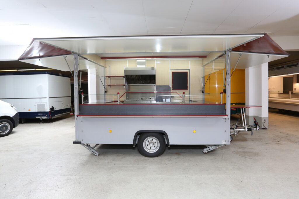 3 Verkaufsseiten, 2 LIEBHERR Kühlschränke, UBERT-Bratgerät mit 60 cm Rostbräter und 2 Schaschlikpfannen (14 KW), Doppelfriteuse mit verstärkter Leistung  (16,25 KW),  Bainmarie und Dunstabzugshaube. Anhänger ist in einem Top-Zustand.