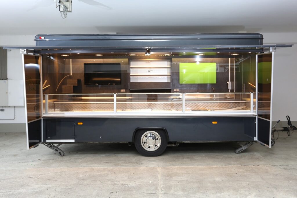 Molkereiprodukte Verkaufsanhänger mit 5,00 m Panorama Rechteck-Kühltheke, verstärkte Kühlleistung, 2 Kühlfächer, 1 Kühlschrank und Kühlregal, Unterspannungsschutz, Sanftanlauf für Thekenkühlung, Alu Seitenblenden, Käsetreppe, Beleuchtung in der Verkaufsklappe, Werbebildschirm uvm.