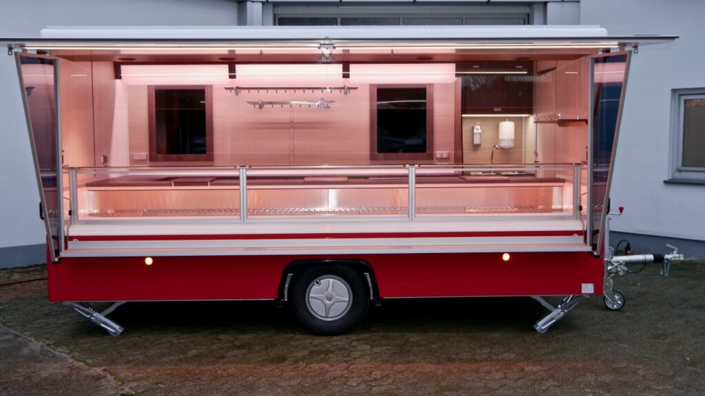 Verkaufsanhänger CLEVERplus 3, Neufahrzeug:-beheizte Körperschutzkante, hochwertige Verkaufskühltheke Optima mit verstärkter Kühlleistung, diverses Thekenzubehör (z.B. Waagenplatte), Kassenschublade, Werbetafel mit Glasschriftfeld