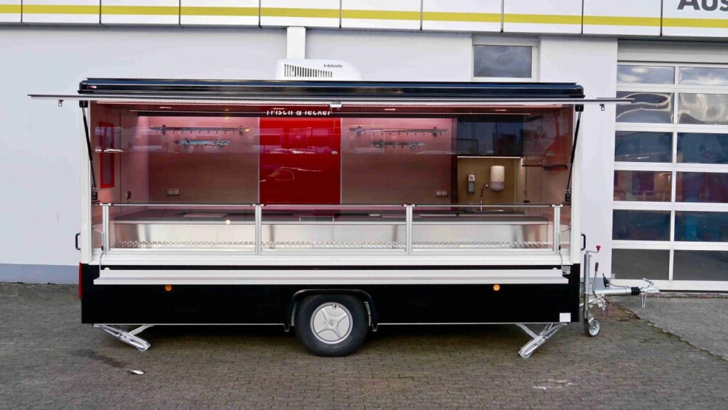 Verkaufsanhänger CLEVERplus 3, Neufahrzeug:-Verkaufskühltheke Optima, diverses Thekenzubehör (z.B. Waagenplatte), Kassenschublade, Lampenblende mit Sichtfeldern-Beheizte Körperschutzkante-Deckenklimagerät