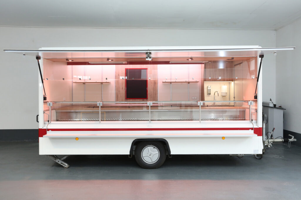 Sehr gepflegter Fleisch- und Wurstwaren Verkaufsanhänger mit Kühltheke 670 mm Auslage, 1 Kühlfach, senkrechter Thekenverglasung, BÄRO-CX-Strahler, Infrarot Deckenheizung, Windschutzverglasung in Verkaufsöffnung, Acrylglas-Abdeckscheiben in Thekenöffnung, 2000 W. Untertischboiler mit GK-Wasseranschluß uvm.