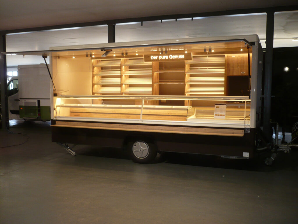 Gepflegter Verkaufsanhänger mit neuster LED-Lichttechnik und hoher Lichtleistung. Die Brotborde haben Aluminium-Rundstäbe und gehen über 4  Etagen an der Rückwand, ebenso befindet sich dort ein Handelswarenbord und Platz für eine Kaffeemaschine. Pletz für Brotschneidemaschine an der Rückwand.