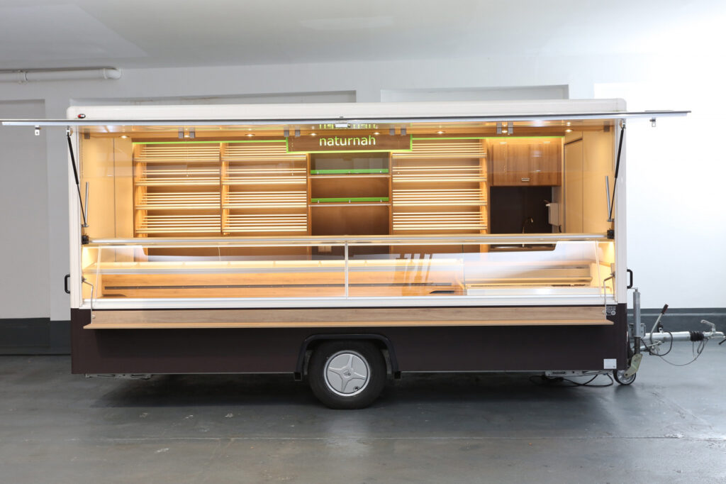 Backwaren Verkaufsanhänger--1,30 m Kühltheke 5 Bleche 60 x 40 cm (3 Bleche Präsentation, 2 Bleche Bevorratung)-3,20 m Backwarentheke für 8 Bleche und zusätzlicher Zwischenablage-über 4 Etagen Aluminium Brotbordsystem-unterhalb vom Brotbordsystem Präsentations- und Ablagefläche