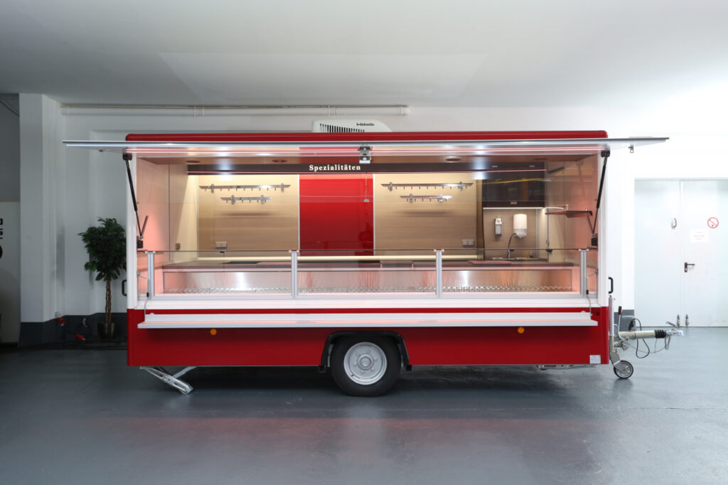 Sehr gepflegter Verkaufsanhänger mit verstärkter Kühlleistung ausgelegt auf eine Umgebungstemperatur von 32°C. Thekenauslage 740 mm mit senkrechtem Panorama-Thekenaufsatz, 2 Kühlauszüge, Deckenklimagerät, BÄRO LED-Beleuchtung Intara CX.