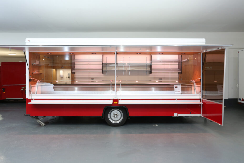 Sehr junger und gepflegter Verkaufsanhänger. Kühlanlage mit verstärkter Leistung 32°, Fußbodenerwärmung, beheizte Körperschutzkante, Bodenschräge am Heck, verbreiterte Eingangstür, Staufach unter Theke und uvm.