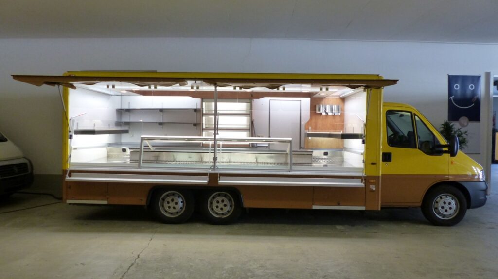4,80 m Kühltheke mit Quertheken ca. 800mm jeweils an Stirn- und Heckseite, zusätzlich eutektische Rohre zur Unterstützung bzw. Fahrtkühlung, automatische Verdampferenteisung, digitale Regelung der Kühlschränke, Kühlregal in 3 Etagen mit elektrischem Rollo, 3 Kühlfächer unter Theke, BÄRO-Food-Light Mini-Strahler über Theke mit zusätzlichen Parabol-Spiegelrasterleuchten, Gasheizung, Rückfahrkamera.