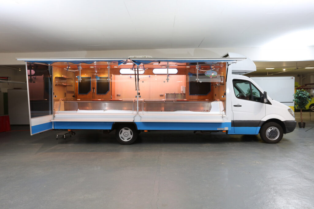 Wochenmarkt-Verkaufsmobil mit Panorama-Kühltheke mit verstärkter Kühlleistung, großer Hochkühlschrank mit ca. 1.450 Ltr. Inhalt, 2 Kühlfächer unter Theke, Deckenklimagerät, Alu-Seitenblenden.
