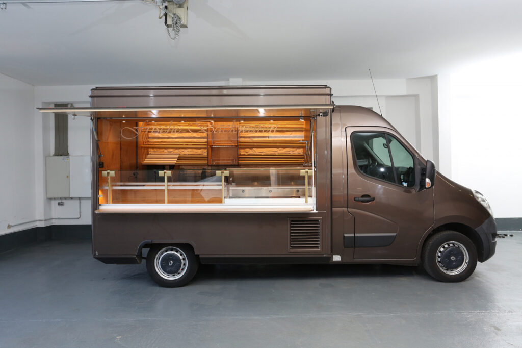 Sehr schönes Backwaren Verkaufsmobil im Landhausstil mit Steinwand-Optik  und Holzdekoren an der Verkaufsrückseite.