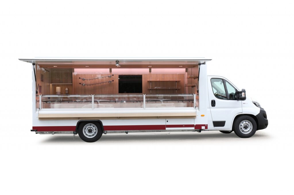 Verkaufsmobil für Fleisch & Wurstwaren mit einer Innenlänge von 5 m. Das Fleischermobil ist mit einer 5,00 m OPTIMA-Verkaufskühltheke mit einer stillen Kühlung, inklusive integriertem Ultraschall-Luftbefechtungssystem ausgestattet. Die Kühlanlage ist für einen Umgebungstemperatur von 32°C ausgelegt. Unterhalb der Theke ist ein Doppelkühlfach mit zwei Kühlauszügen für jeweils 2 E-Kisten. Senkrechter Thekenaufsatz mit LED-Thekenbeleuchtung. An der Rückwand sind Hakenschienen aus Edelstahl sowie eine aufgesetzte Glaswerbetafel montiert. BÄRO-LED Beleuchtung im Verkaufsinnenraum. Basisfahrzeug Fiat Ducato 40 mit 140 PS, 6d-Temp. Im Basisfahrzeug ist eine Beifahrerdoppelsitzbank, Allwetterbereifung, eine manuelle Klimaanlage und ein Radio enthalten.