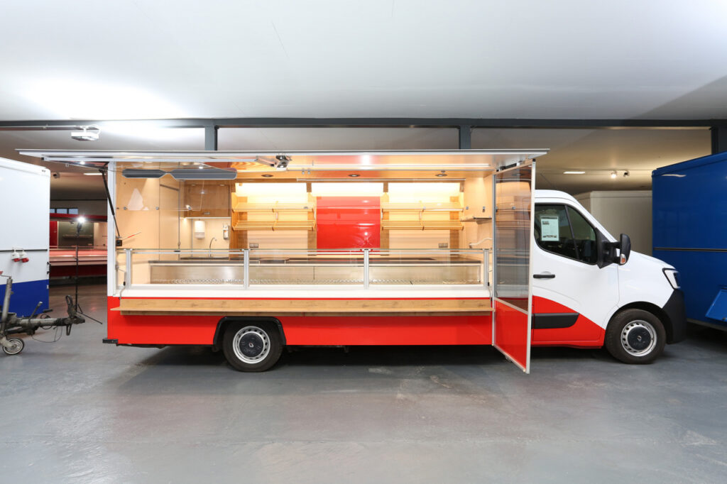 Verkaufskühltheke mit 740 mm Auslage und 32° Kühlung, 3 Kühlfächer unter Theke, LED BÄRO CX-Einbaustrahler, LED-Lichtband in Theke und unter Verkaufsklappe, Forming-Deckenlichtkasten, Alu-Seitenblenden, beheizbare Körperschutzkante, Windschutz-Verglasung, Unterschränke, Brotborde, Werbetafel mit Glasschriftfeld, Renault mit Klang & Klima Paket sowie Beifahrer-Doppelsitzbank.