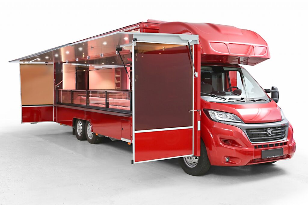 Mit Fahrtkühlung ausgestattete Verkaufskühltheke mit 32°C Kühltheke und jeder Menge Bevorratungsmöglichkeiten. Senkrechter Thekenaufsatz für eine gute Warenpräsentation, Dachklimagerät für Kühlung oder heizen des Verkaufsraumes. Rückwand ist durch ein Flachenlicht beleuchtet, darauf liegend Präsentationsborde und Hakenschienen. BÄRO CX Strahler über der Theke sorgen für eine optimale Warenausleuchtung. Unterhalb der Verkaufsklappe befinden sind Seitenblenden als Wind- und Wetterschutz. Basisfahrzeug Fiat Ducato mit einer Beifahrerdoppelsitzbank, Radio und Nebelscheinwerfern. Über einen Monitor im Fahrerhaus kann die Rückfahrvideokamera bedient werden.