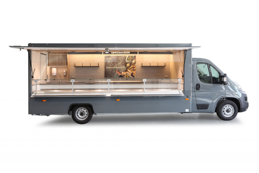 Feinkost Verkaufsmobil-5m Umluft-Kühltheke und einem Doppelkühlfach für 4 E-Kisten. -Austauschbares Werbebild, Regale und LED Beleuchtung.-Fiat Ducato mit 120 PS, Doppelsitzbank, automatische Klimaanlage und Allwetterbereifung